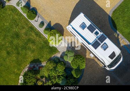 Camping e Turismo tema. Moderno Camper Van con pannelli solari installato stare su Cobble Stone viale in attesa di una nuova destinazione. Vista aerea Foto Stock