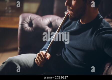 bell'uomo con tubo di tabacco in bocca. primo piano vista laterale tagliata foto. tempo libero, hobby Foto Stock