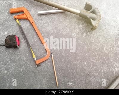 Nastro di misurazione e seghetto a mancia sul pavimento del cantiere Foto Stock