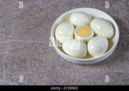 Uova sbucciate bollite senza guscio su sfondo grigio. Ingredienti per cucinare. Foto Stock