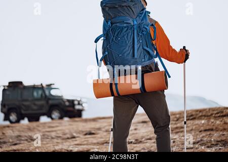 Uomo viaggiatore con bastoni da trekking che saliscono la montagna Foto Stock
