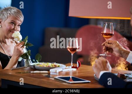 Elegante caucasica, bella, donna anziana guarda il marito, grato per la rosa bianca presente. Ottenere complimento. Donna bionda matura innamorato dell'uomo. T Foto Stock
