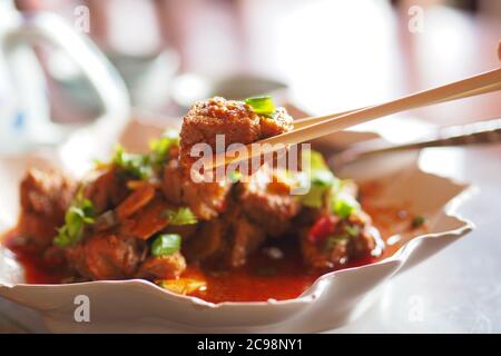 Maiale piccante fritto in padella su bastoncini Foto Stock