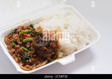 Pad Krapao Moo SAP o uova fritte del secolo con sminuzzate Maiale e foglia di basilico croccante sul riso in schiuma Box per portare a casa Foto Stock