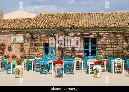 Tavoli e sedie colouful in Piazza Regina Margherita in frazione Marzamemi, Sicilia Foto Stock