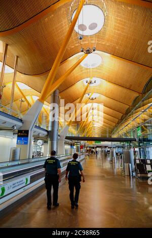 28 luglio 2020, Aeroporto Barajas, Madrid, Spagna: Guardie civili / ufficiali civili della Guardia camminano attraverso la vicina area lounge delle porte di partenza empy dell'edificio del Terminal 4S dell'Aeroporto di Barajas. Un numero ridotto di voli è ora operativo tra i paesi europei dopo il blocco per controllare il coronavirus della covid-19, e i governi hanno messo in atto un sistema di ponti aerei per facilitare i viaggi e il turismo. La Spagna ha visto una serie di nuovi focolai negli ultimi giorni, spingendo il governo britannico ad annunciare che le persone che tornano nel Regno Unito dalla Spagna dovrebbero essere in quarantena per 14 giorni all'arrivo. Foto Stock