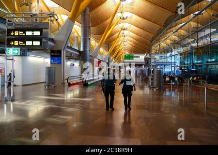 28 luglio 2020, Aeroporto Barajas, Madrid, Spagna: Guardie civili / ufficiali civili della Guardia camminano attraverso la vicina area lounge delle porte di partenza empy dell'edificio del Terminal 4S dell'Aeroporto di Barajas. Un numero ridotto di voli è ora operativo tra i paesi europei dopo il blocco per controllare il coronavirus della covid-19, e i governi hanno messo in atto un sistema di ponti aerei per facilitare i viaggi e il turismo. La Spagna ha visto una serie di nuovi focolai negli ultimi giorni, spingendo il governo britannico ad annunciare che le persone che tornano nel Regno Unito dalla Spagna dovrebbero essere in quarantena per 14 giorni all'arrivo. Foto Stock