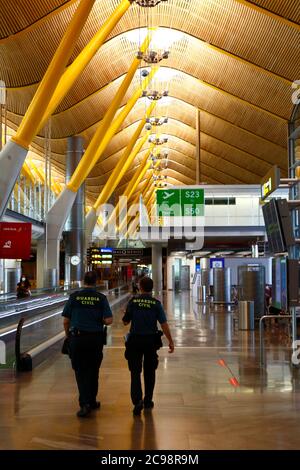 28 luglio 2020, Aeroporto Barajas, Madrid, Spagna: Guardie civili / ufficiali civili della Guardia camminano attraverso la vicina area lounge delle porte di partenza empy dell'edificio del Terminal 4S dell'Aeroporto di Barajas. Un numero ridotto di voli è ora operativo tra i paesi europei dopo il blocco per controllare il coronavirus della covid-19, e i governi hanno messo in atto un sistema di ponti aerei per facilitare i viaggi e il turismo. La Spagna ha visto una serie di nuovi focolai negli ultimi giorni, spingendo il governo britannico ad annunciare che le persone che tornano nel Regno Unito dalla Spagna dovrebbero essere in quarantena per 14 giorni all'arrivo. Foto Stock