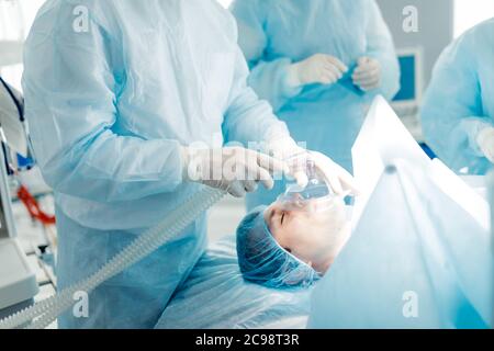 l'uomo malato ha difficoltà a respirare attraverso il naso, così i medici che gli danno la maschera. primo piano vista laterale foto. Foto Stock