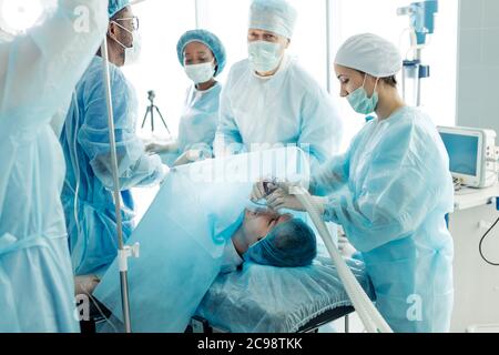 medici attenti e intelligenti che regolano la maschera di ossigeno sul paziente nella stanza dell'ospedale. primo piano della foto Foto Stock