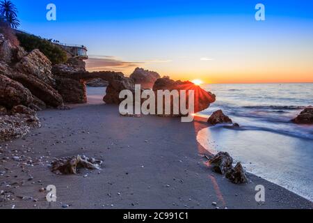 Alba sulla costa spagnola. Balcon Europa nella città di Nerja sulla Costa del Sol. Mare e rocce con arco sulla costa in Andalusia. Spiaggia di sabbia Foto Stock