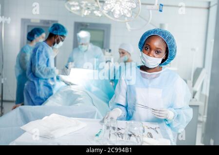 buon medico americano che tiene il forcipe e che posa alla macchina fotografica. occupazione favorita Foto Stock