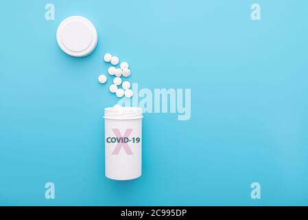 Anti COVID - 19 pillole in bottiglia di plastica bianca su sfondo blu, pillole anti virus, farmaci, idea medica. Foto Stock