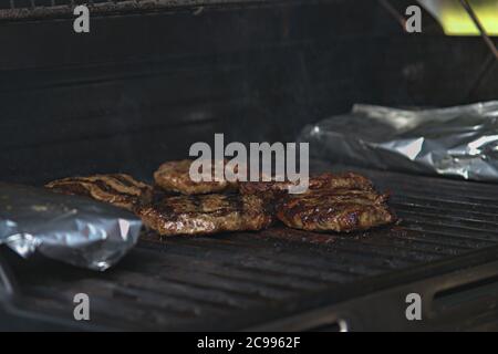 persona che capovolge hamburger al barbecue con le fiamme Foto Stock