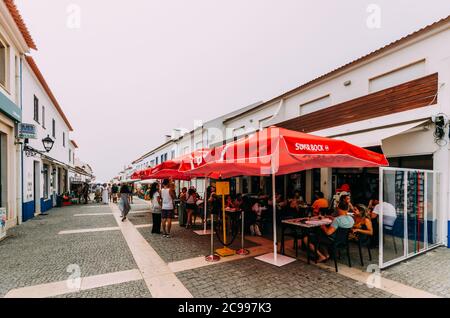 Gente che si rilassa ai caffè a Pictureque Porto Covo in Portogallo Foto Stock