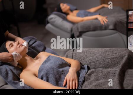 belle donne caucasiche sane rilassarsi sul tavolo da massaggio, cura del corpo in salone termale, massaggio su viso, testa, collo, spalle Foto Stock