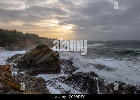 Onde che infrangono e cielo spettacolare sulla costa rocciosa del Pacifico, presso lo Shore Acres state Park, vicino a Charleston, Oregon Foto Stock