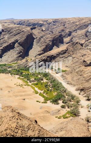Tipico terreno montuoso roccioso scolorito e arido stratificato e letto di fiume seccato nel deserto del Namib sulla Skeleton Coast, Namibia, Africa sudoccidentale Foto Stock