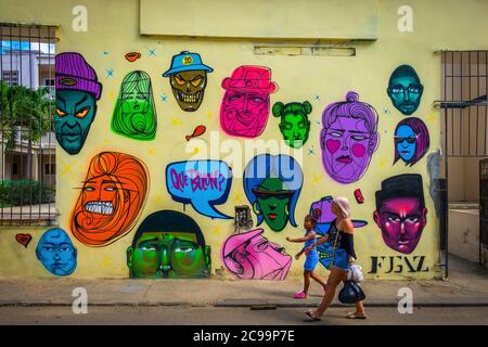 L'Avana, Cuba, luglio 2019, una madre e una figlia camminano vicino a un murale nella parte vecchia della città Foto Stock