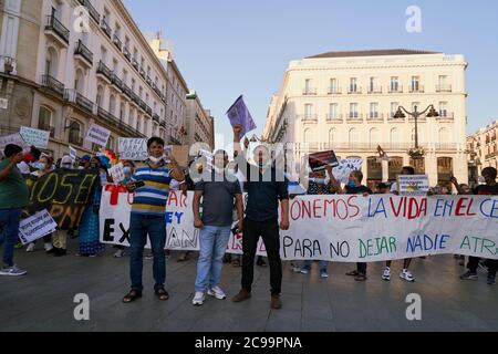Tre uomini si trovano davanti ai manifesti Tumbar la racista ley de extranjeria e Ponemos la vida en el centro, Puerta del Sol, Madrid, 2020 Foto Stock