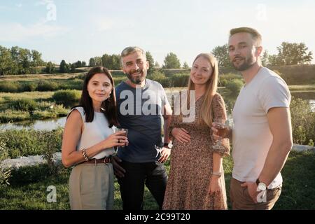 Ritratto di due giovani coppie in piedi all'aperto e sorridendo con la macchina fotografica che riposano nel paese Foto Stock