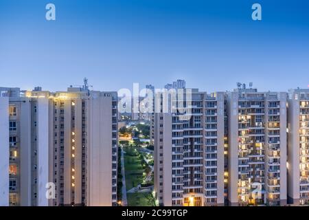 Crepuscolo aereo di bouldings con calde luci arancioni che brillano fuori degli uffici e delle residenze di recente costruzione Foto Stock