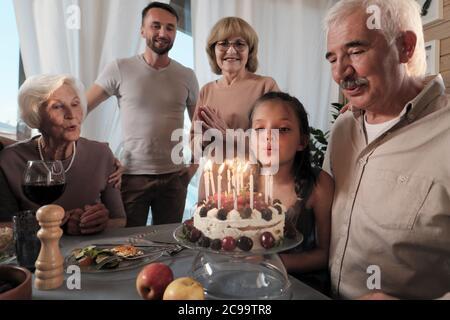 Grande famiglia felice che festeggia il compleanno del loro padre con torta di compleanno al tavolo a casa Foto Stock