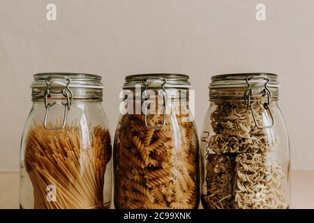 Tre contenitori in vetro pieni di ingredienti alimentari secchi non cotti. Riso, pasta, farina, zucchero. Foto Stock