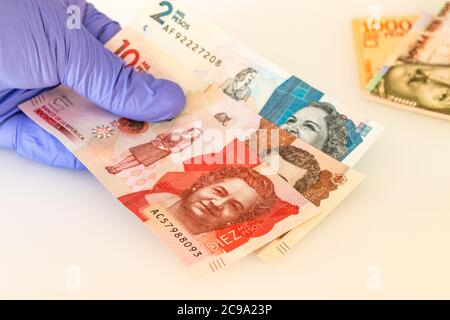 Moneta colombiana, banconote in pesos tenute in guanti di gomma. Il concetto di economia e minacce finanziarie durante l'epidemia di Coronavirus Foto Stock