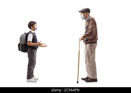 Foto di profilo a lunghezza intera di uno scolaro che parla con il nonno e indossa una maschera protettiva isolata su sfondo bianco Foto Stock