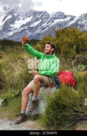 tramper kiwi della Nuova Zelanda scattare foto selfie del telefono durante l'escursione sulla pista di Hooker Valley a Mt Cook. Estate escursionista mangiare pausa pranzo durante Foto Stock