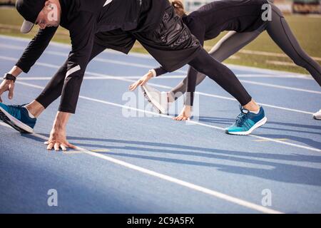 primo piano con foto ritagliata. adatta le persone che riscaldano le gambe prima della gara. giovani che fanno esercizi per lo stretching Foto Stock