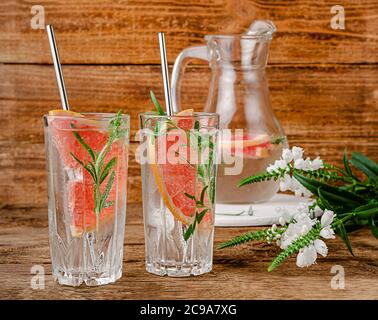 Acqua infusa di pompelmo con tonico e rosmarino su sfondo ligneo. Spazio di copia Foto Stock