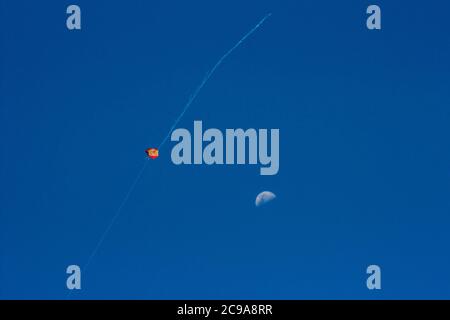 Aquilone colorato che vola in alto in cielo blu profondo e il luna Foto Stock