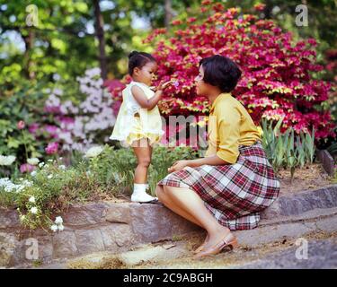 1970 MADRE AFROAMERICANA SEDUTA IN PRIMAVERA GIARDINO CON FIGLIA TODDLER INDOSSANDO GIALLE GIALLE ABITI MOM INDOSSANDO GONNA PLAID - KJ5369 PHT001 MADRI HARS VECCHIO TEMPO NOSTALGIA VECCHIO MODO 1 GIOVANE COMUNICAZIONE FAMIGLIE ADULTE GIOIA STILE DI VITA FEMMINE CASA VITA NATURA COPIA SPAZIO AMICIZIA FULL-LENGTH DONNE FIGLIE PERSONE PRENDERSI CURA PLAID FELICITÀ SCOPERTA AFRO-AMERICANI AFRO-AMERICANO BASSO ANGOLO NERO ETNIA ORGOGLIO CONNESSIONE ELEGANTI FIORI COOPERAZIONE CRESCITA GIOVANI MAMME PRIMAVERA PIETRA MURO TOGETHERNESS GIOVANE DONNA ADULTA BAMBINO RAGAZZA VECCHIO STILE AFRO-AMERICANI Foto Stock