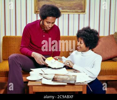 1970 AFRICAN-AMERICAN COUPLE LIVING ROOM TALKING AT COFFEE TABLE REVISIONARE PAINT CHIPS SWATCH HOME REMODEL BROCHURE - KS11151 HAR001 HARS COMUNICAZIONE VERNICE LAVORO DI SQUADRA GIOIA SODDISFAZIONE STILE DI VITA SODDISFAZIONE FEMALE SPOSATO STUDIO SHOT CONIUGE HUSBAND HOME VITA COPIA SPAZIO AMICIZIA MEZZA LUNGHEZZA SIGNORE PERSONE MASCHI PIANIFICAZIONE PARTNER SOGNI FELICITÀ DISCUTERE NUOVA CASA OPUSCOLI AFROAMERICANI AFROAMERICANI SCELTA ETNIA NERA ORGOGLIO VISO CAPELLI SORRISI CONNESSIONE REVISIONE GIOIOSA ELEGANTE COOPERAZIONE MID-ADULT UOMO MID-ADULT DONNA BASETTE STRIPED CARTA DA PARATI TOGETHERNESS Foto Stock