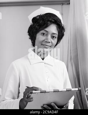 1970 SERIOUS AFRICAN-AMERICAN WOMAN NURSE IN UNIFORM GUARDANDO LA FOTOCAMERA INSERENDO LE INFORMAZIONI DEL PAZIENTE NELLA CARTELLA DELL'OSPEDALE - N2485 HAR001 HARS GIOVANE ADULTO INFORMAZIONI STILE DI VITA FEMMINE LAVORI SALUTE MALATTIA COPIA SPAZIO SIGNORE MEZZA LUNGHEZZA FISICA FITNESS PERSONE ISPIRAZIONE PROFESSIONE CURA ESPRESSIONI DI FIDUCIA B&W CONTATTO CON L'OCCHIO ASSISTENZA SANITARIA ABILITÀ PROFESSIONE ABILITÀ PREVENZIONE DEL BENESSERE FORZA HEALING AFROAMERICANI CORAGGIO AFROAMERICANO DIAGNOSI CARRIERA CONOSCENZA ETNIA NERA ORGOGLIO SANITÀ AUTORITÀ COMPROMISSIONE DELLE COMPETENZE TRATTAMENTO CONNESSIONE CONCETTUALE ELEGANTE SOSTEGNO PIACEVOLE Foto Stock