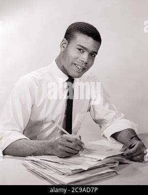 1950S 1960S UOMO AFROAMERICANO CHE TIENE LA MATITA SOPRA IL MUCCHIO DI PAPERWORK CHE INDOSSA ROTOLATO SU SHIRTSLEEVES NECKTIE GUARDANDO LA MACCHINA FOTOGRAFICA - N286 HAR001 HARS GIOVANE ADULTO SODDISFATTO GIOIA STILE DI VITA SODDISFAZIONE IMPIEGATO ROTOLATO LAVORI STUDIO SHOT MANAGER COPY SPACE MEZZA LUNGHEZZA PERSONE MASCHI PROFESSIONE DIRIGENTI B&W OCCHIO CONTATTO FILE ABILITÀ OCCUPAZIONE FELICITÀ ABILITÀ ALLEGRO AFROAMERICANI AFROAMERICANI CARRIERE NERO ETNIA ORGOGLIO SU CARTELLE DI LAVORO NECKTIE OCCUPAZIONI SORRISI BOSS CONNESSIONE GIOIOSO DIPENDENTE SHIRTSLEEVES MANAGER GIOVANE UOMO ADULTO NERO E BIANCO HAR001 VECCHIO STILE AFROAMERICANI Foto Stock