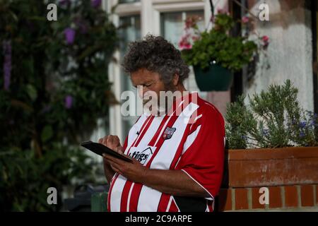 Londra, 29 luglio 2020 UN sostenitore controlla il suo telefono mentre la partita si avvicina all'esterno di Griffin Park l'ultima notte di calcio nella loro casa storica (dal 1904) prima di trasferirsi al loro nuovo campo, il Brentford Community Stadium. Hanno vinto la semifinale del playoff per raggiungere la finale Andrew Fosker / Alamy Live News Foto Stock