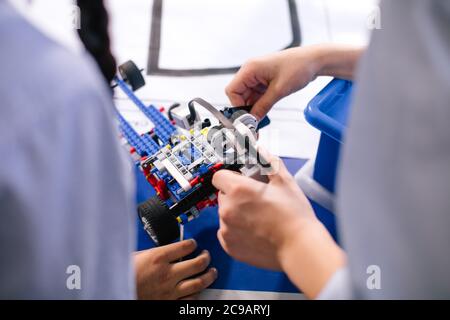 Primo piano delle mani dei ragazzi durante la creazione di un robot in laboratorio, lezioni di robotica. Sviluppo precoce, fai da te, innovazione, concetto di tecnologia moderna Foto Stock