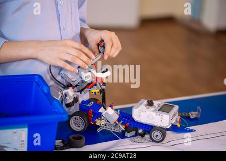 Primo piano delle mani dei ragazzi durante la creazione di un robot in laboratorio, lezioni di robotica. Sviluppo precoce, fai da te, innovazione, concetto di tecnologia moderna Foto Stock