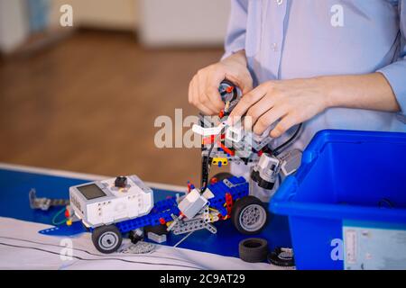 Primo piano delle mani dei ragazzi durante la creazione di un robot in laboratorio, lezioni di robotica. Sviluppo precoce, fai da te, innovazione, concetto di tecnologia moderna Foto Stock