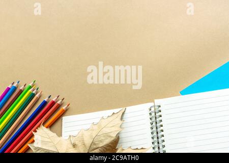 Forniture scolastiche su sfondo beige e foglia d'autunno, posa piatta, spazio copia. Foto Stock