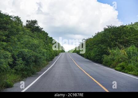 Strada per la montagna / UNA lunga strada dritta che conduce verso un albero verde natura sulle montagne, strada asfaltata in Thailandia Foto Stock