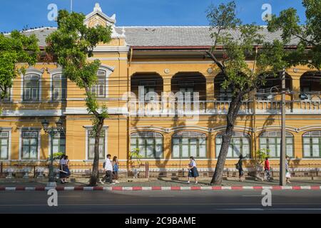 Gli studenti sulla strada per le lezioni passano davanti alla storica Scuola Suan Gularb Witthalayai, fondata nel 1882 e costruita in stile europeo; Bangkok, Thailandia Foto Stock