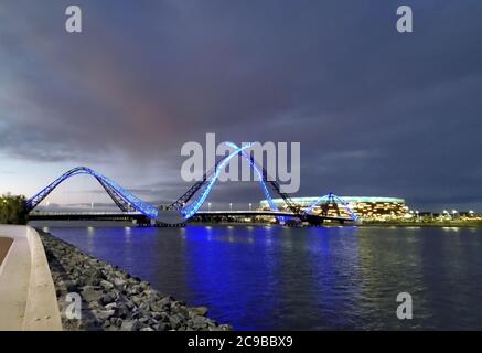 Vista notturna del ponte Perth Matagarup e con luci al neon blu e riflessi sul fiume Swan. Oktus Stadium con cielo scuro sullo sfondo. Foto Stock