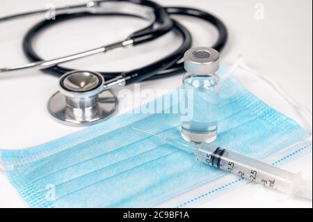 Concetto medico con siringa e fiala su maschera monouso. Foto Stock