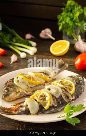 Carassius al forno al forno con limone e spezie in lamina, carpa crogiana di pesce di fiume cotta Foto Stock