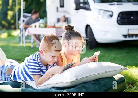 Bambini con telefono cellulare in campeggio Foto Stock