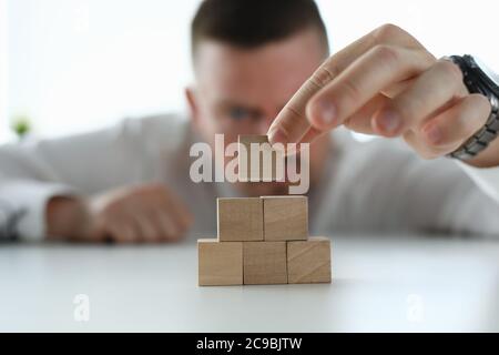 Un uomo impila blocchi di legno su un tavolo da vicino Foto Stock